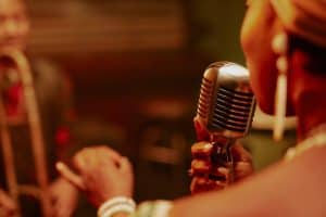 Over shoulder shot of unrecognizable Black woman singing in microphone on stage at jazz concert
