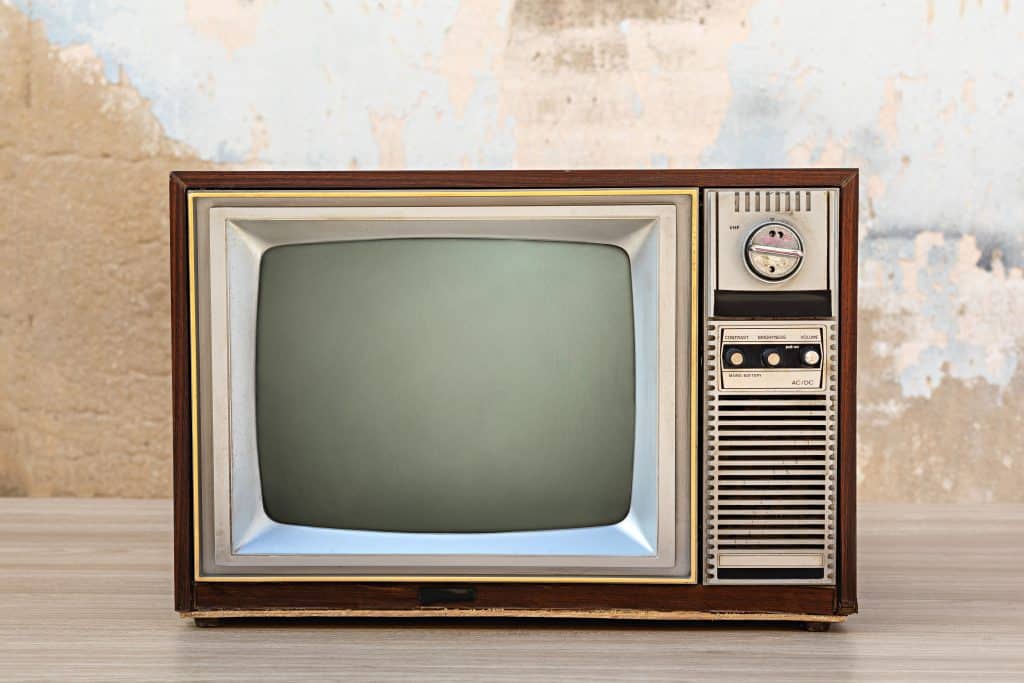 Retro old tv with blank screen on wooden table with old concrete wall background, front view