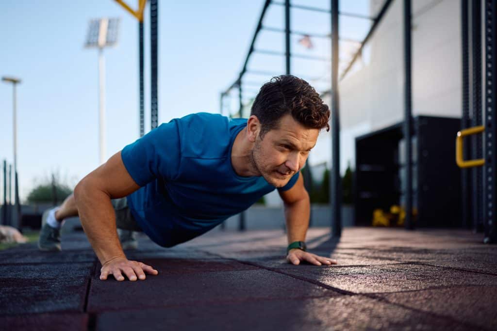 Male athlete exercising push-ups during strength training in outdoor gym. Copy space.