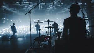 Music band group silhouette perform on a concert stage. silhouette of drummer playing on drums audience holding cigarette lighters and mobile phones