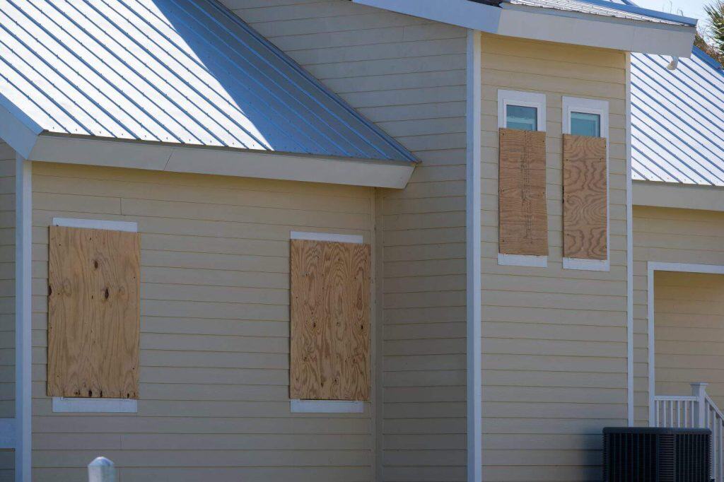 Boarded up windows with plywood storm shutters for hurricane protection of residential house. Protective measures before natural disaster in Florida