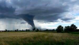 Tornado forming over farmland, dramatic storm clouds touching ground