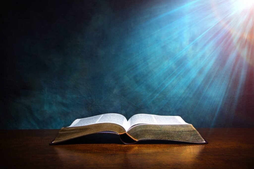 Open Bible on a wood table with light coming from above. ( Church concept. )