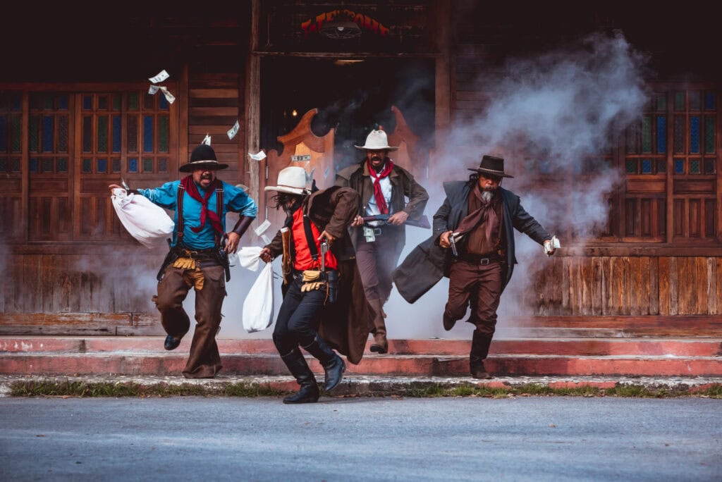 Cowboys group showing action success bank rob with fighting gun and a lot of money from rob the bank with white smoke vintage style background
