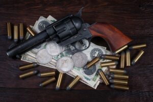 Old west Colt Peacemaker and US banknotes and silver certificates with silver dollar coins and .45 caliber revolver ammunitions background