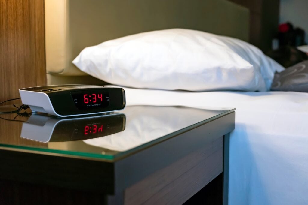 Clock radio alarm at the desk beside of a bed 