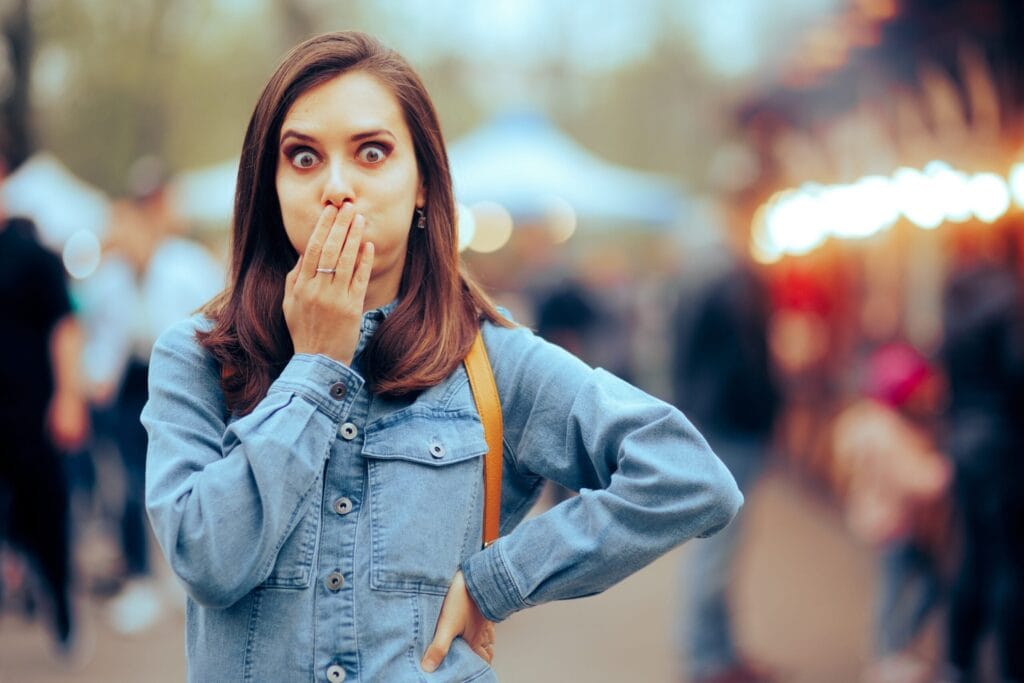 Woman feeling Sick Covering her Mouth at Local Funfair. Ill girl suffering from indigestion after eating some stress food