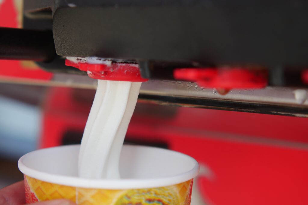 Closeup of Soft Serve Ice Cream Machine Dispensing Vanilla Ice Cream into a Cone