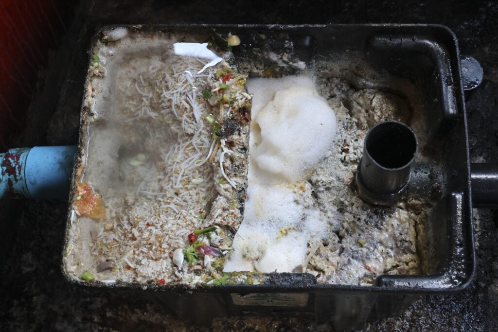 Dirty grease trap full of unsanitary food waste and grime, disgusting clogged mess