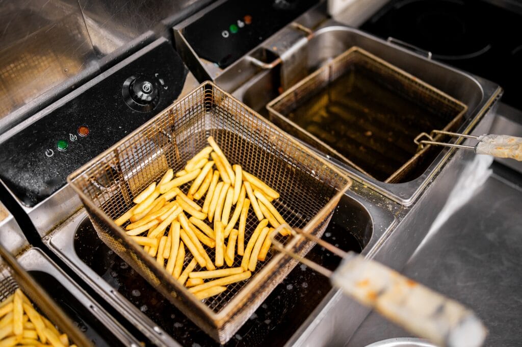 French fries frying in a commercial deep fryer in a restaurant kitchen.