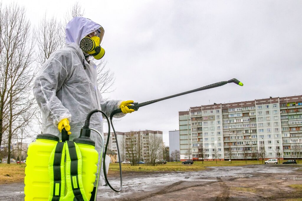 exterminator in a work suit against the background of houses