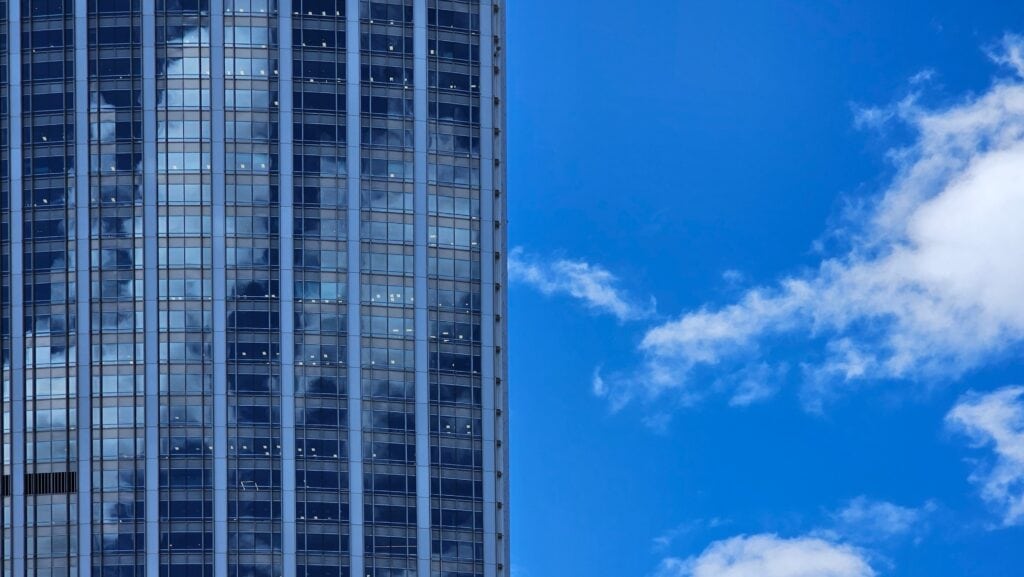 The glass curtain wall building in Xinyi District, Taipei City, Taiwan, contrasts with the blue sky and white clouds