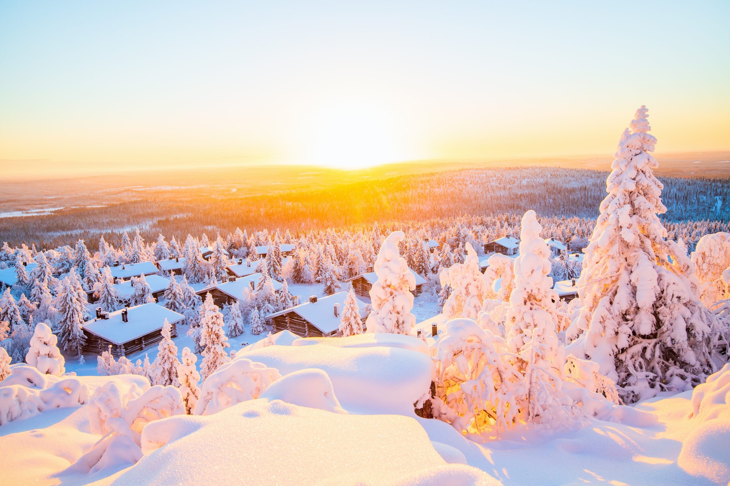 Stunning sunset view over wooden huts and snow covered trees in Finnish Lapland