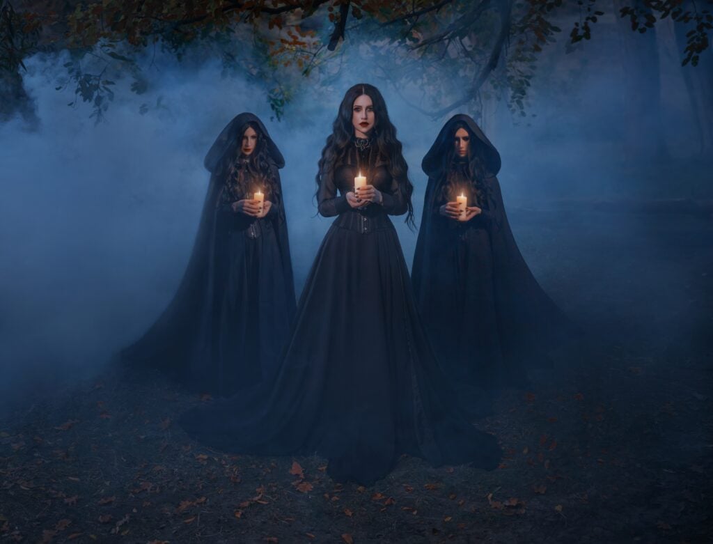 Group of womans walking in night forest tree, holding candles in hands, mystical cult three girls priestesses. Black clothes dress cape hood on head. gothic queen with maids. Dark long hair. art photo