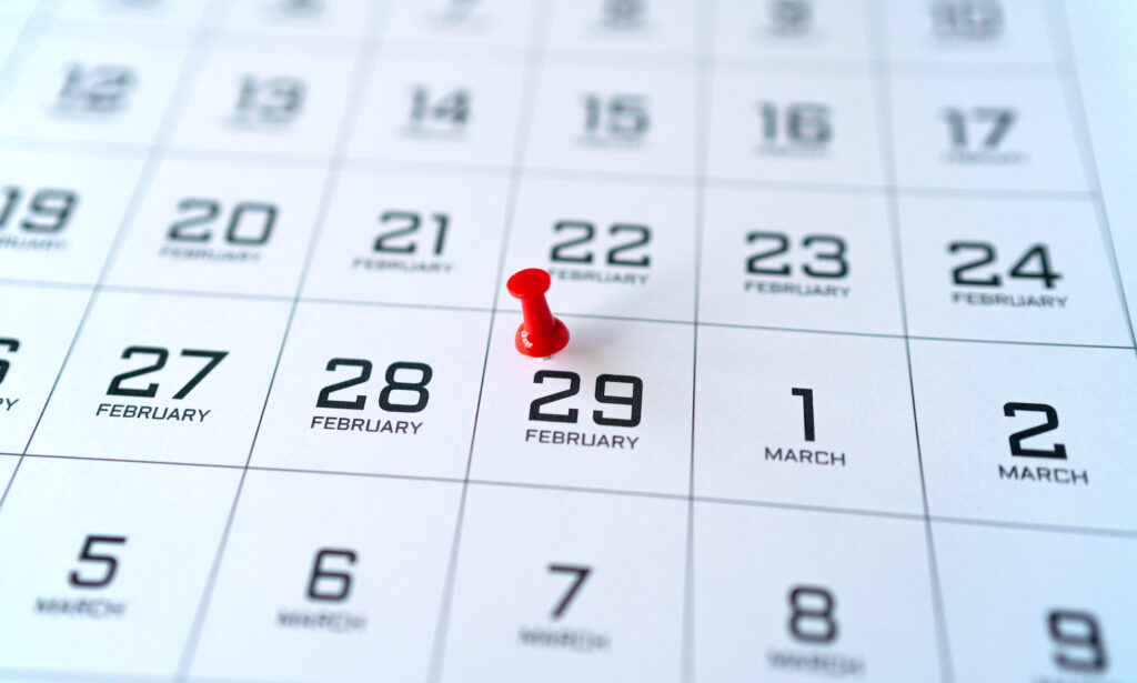 Close up of a part of the calendar of February and March, in black and white. A red pin is marking Leap Day - February 29. 