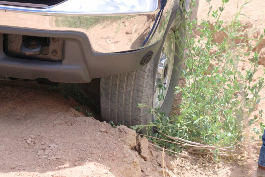 Vehicle wheel stuck in a dry ditch with bushes