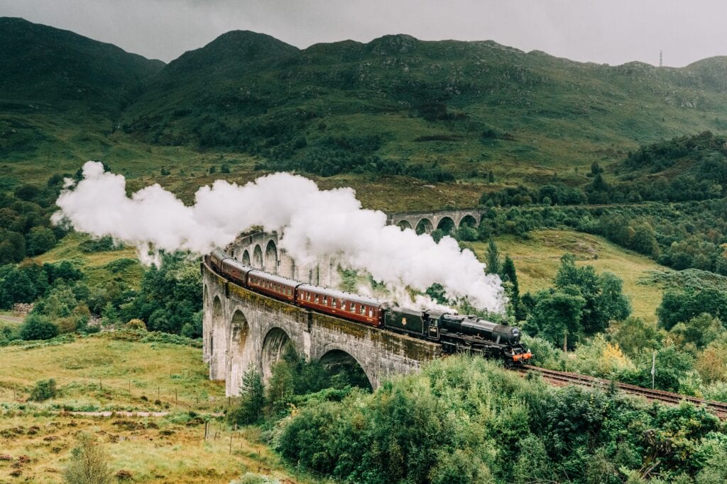 Jacobite steam train crossing the Glenfinnan Viaduct with steam rising from the chimney. Hogwarts Express, Harry Potter.