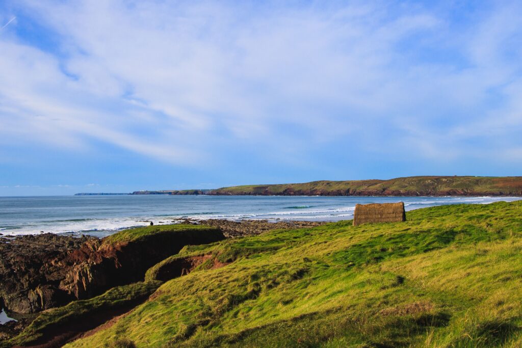 A landscape view of the Freshwater West beach in Wales with Seaweed hut and surf waves in the background