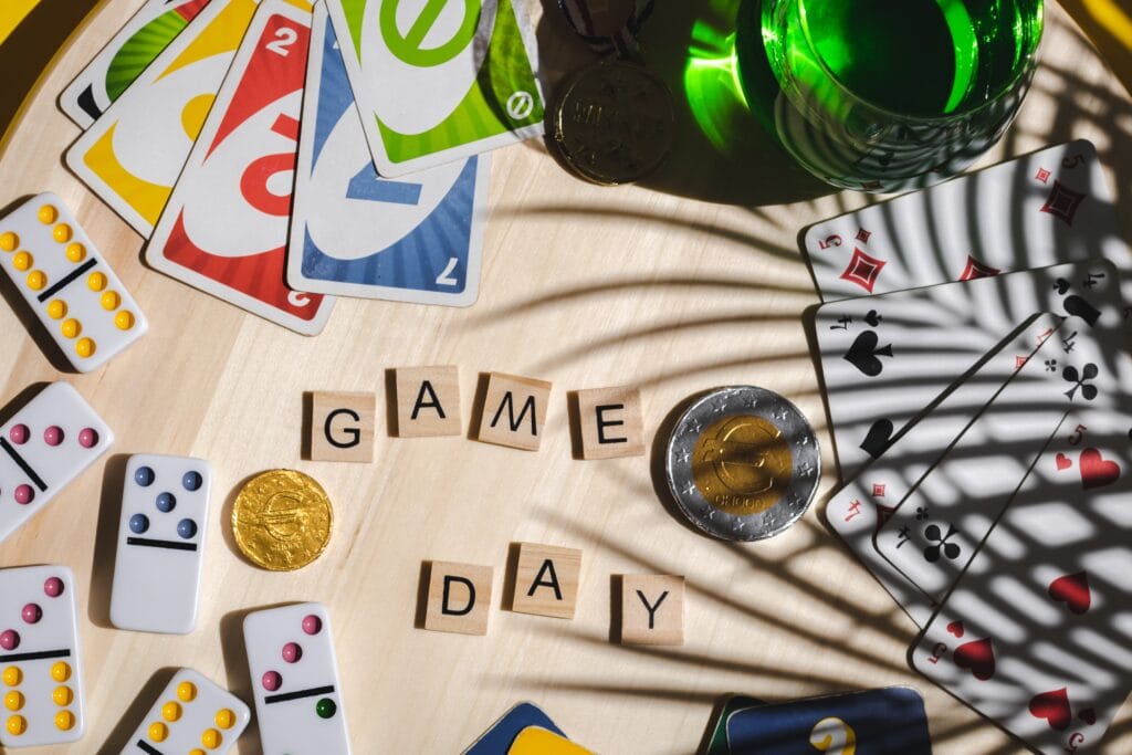 White, game cards, uno, ligretto, green drink house and wooden dice: game day on wooden background. Board game.