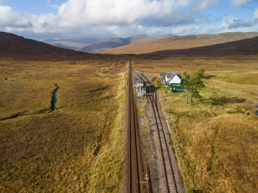 Aerial drone shot of Corrour train station and the west highland way line across Rannoch Moor