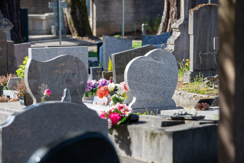 A communal cemetery in France with a grouping of graves and tombs. Funerary space of remembrance marked by a monument, symbols or inscriptions and flowers.
