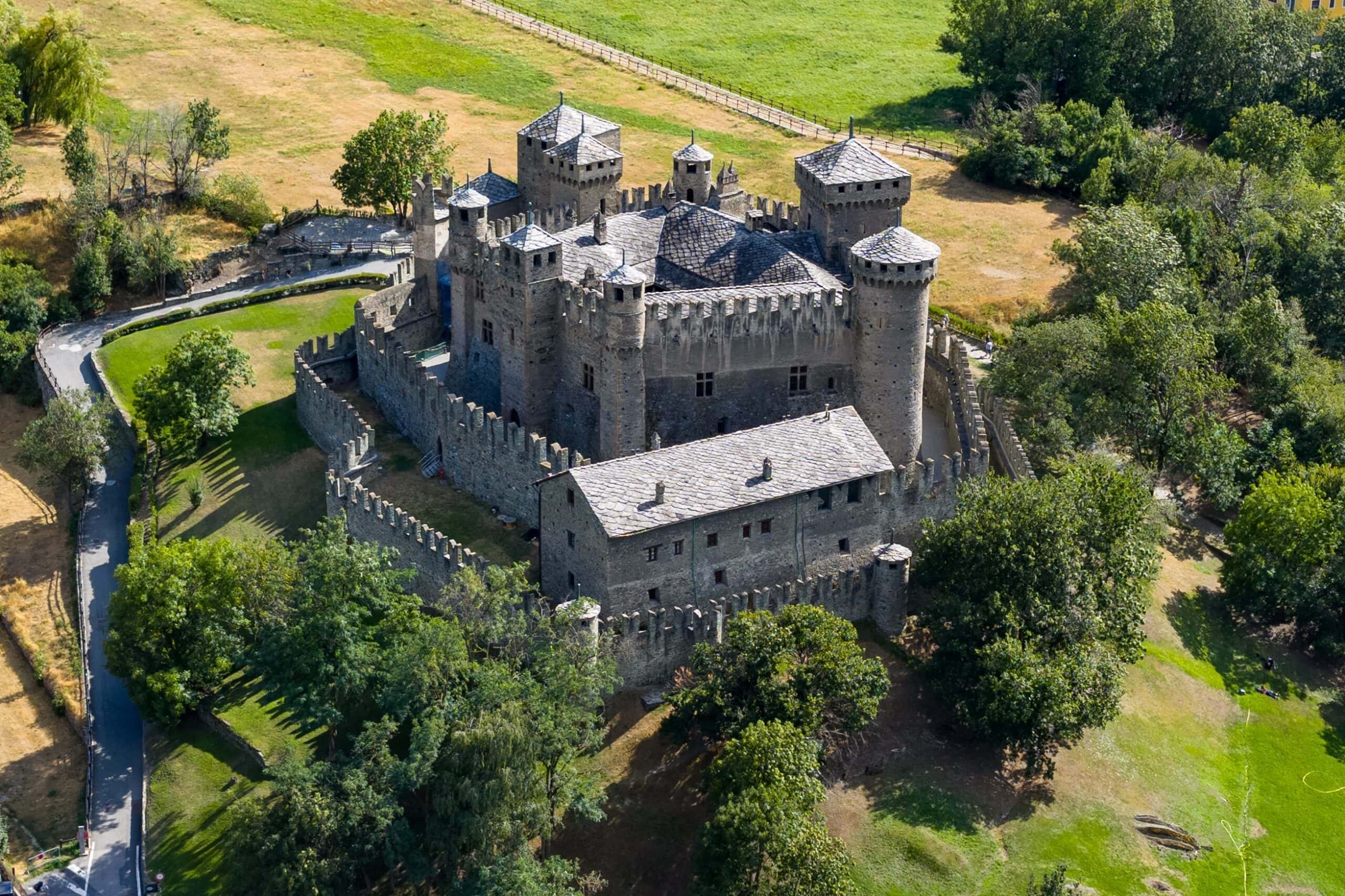 Aerial view of Fénis Castle, medieval stone fortress of the Challant family, dominating fields and village in the Aosta Valley