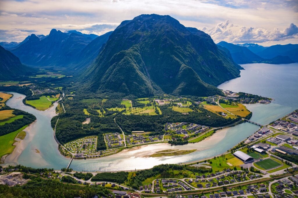 Scenic aerial view of Andalsnes with Rauma River flowing into Romsdalsfjord, surrounded by steep Romsdal mountains, as seen from Nesaksla mountain in Norway.