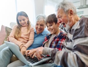 Family grandparents and grandchildren having fun at home using laptop