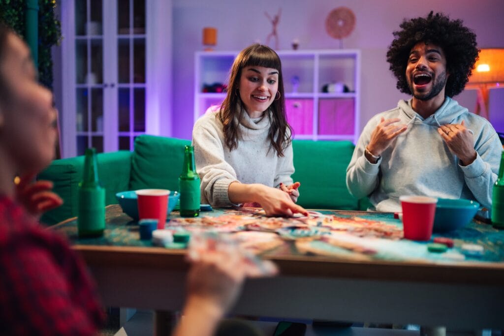 Diverse friends playing a board game together during a relaxed evening, sharing laughter and positive social connection indoors